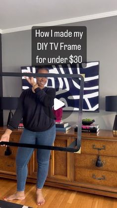 a woman standing in front of a tv holding a sign that says how i made my diy tv frame for under $ 30