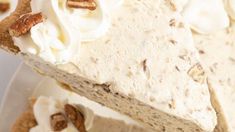 a piece of pie with white frosting and pecans on top is sitting on a plate