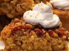 a piece of cake on a plate with whipped cream and pecans in the middle