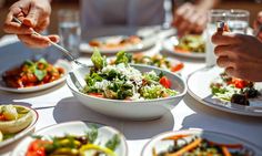 several people are sitting at a table with plates and bowls of food in front of them