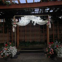 a sign that says better together on the side of a building with flowers around it