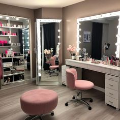 a pink chair sits in front of a vanity with lighted mirrors and lights on it