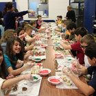 a group of children sitting at a long table eating food