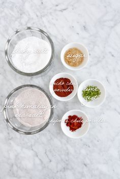 four bowls filled with different types of spices on top of a marble countertop next to each other