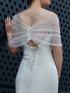 the back of a woman's dress with sheer white fabric and beads on it