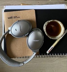 the headphones are next to a cup of tea and a pen on top of a notepad