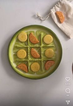 a green plate topped with orange slices on top of a white table next to a napkin