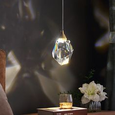 a table with a book, glass vases and a light bulb hanging from the ceiling