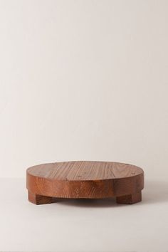 a round wooden table on a white surface