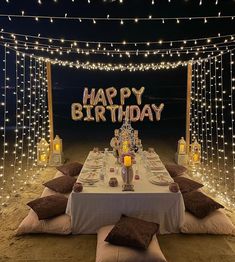 an outdoor birthday party setup with lights and pillows on the ground, along with a sign that says happy birthday