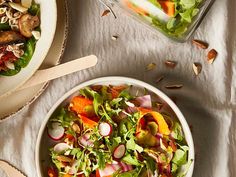 a salad in a bowl with dressing and spoons next to it on a table