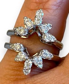 a woman's hand holding two rings with diamonds on them and the middle one has three smaller ones