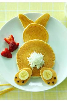 a white plate topped with pancakes covered in toppings and sliced strawberries next to a glass of milk