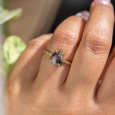 a woman's hand with a ring on it that has an oval shaped diamond in the middle