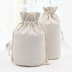 two bags are sitting on a table next to each other, one is white and the other is beige