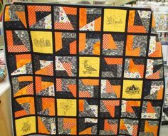 an orange and black quilt on display in a room with many other items around it