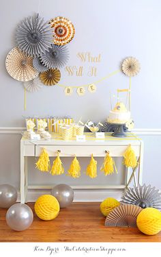 a yellow and gray baby shower party with paper fans, tissue pom poms