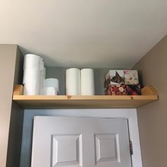 the shelves above the door are filled with rolls of toilet paper and other items for storage