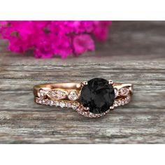 a black and white diamond ring set on top of a wooden table with pink flowers in the background