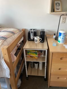 a bedroom with a bed, desk and coffee maker on the nightstand next to it