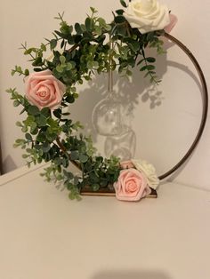 some pink and white flowers are in a glass vase on a table with greenery