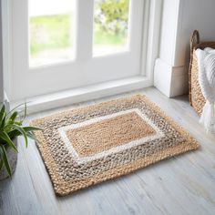 a rug on the floor in front of a window with a potted plant next to it