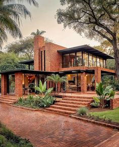 a large brick house surrounded by lush green trees