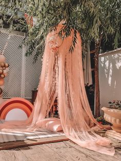 a pink canopy hanging from a tree in the middle of a room with other furniture