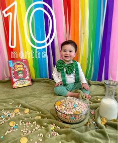 a baby sitting in front of a rainbow backdrop with the words 10 months on it