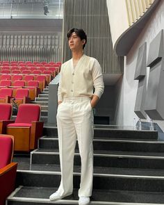 a man standing on some steps in front of an auditorium full of red and pink chairs