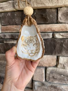 a hand holding up a white and gold tiger ornament