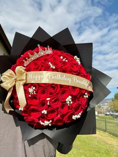 a man holding a large bouquet of red roses with a happy birthday sign on it