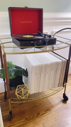 a record player sitting on top of a metal cart filled with books and vinyl records