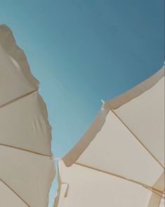 two white umbrellas sitting next to each other under a blue sky