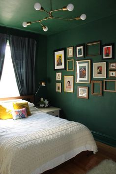 a bedroom with green walls and pictures hanging on the wall, along with a white bed