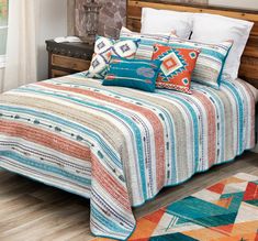 a bed with multi colored bedspread and pillows