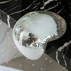 a disco ball sitting on top of a black and white marble counter next to a mirror