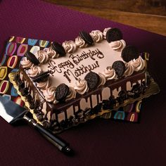 a chocolate cake with white frosting and oreo cookies on top sitting on a table