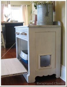 a white cabinet with flowers in it and a cat door on the bottom shelf next to it