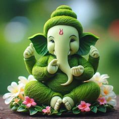 a small statue of an elephant sitting on top of a wooden table next to flowers