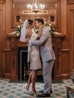 a bride and groom are kissing in front of the fireplace at their wedding ceremony,