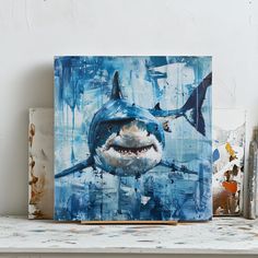 a painting of a shark with teeth on it's face is displayed next to other paintings