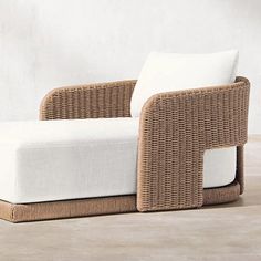 a wicker couch sitting on top of a wooden floor next to a white wall