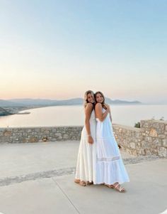 two women standing next to each other near the ocean