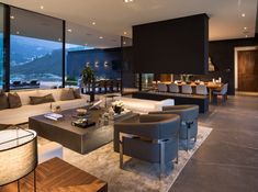 a living room filled with lots of furniture and large windows overlooking the mountains in the distance