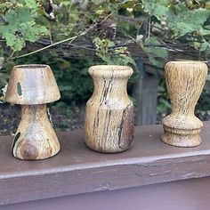 three small wooden vases sitting on top of a shelf next to a tree branch