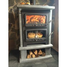 a wood burning stove sitting inside of a kitchen next to a pile of firewood