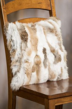 a wooden chair with a furry pillow on it's back and seat cushion in the shape of an animal print