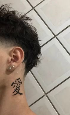 a woman with a tattoo on her neck and behind her ear is looking at the camera