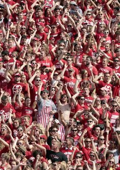 a large group of people in red shirts and sunglasses are standing together with their hands up